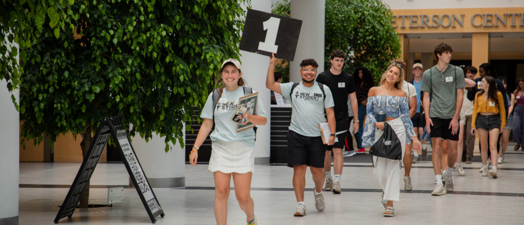 orientation leaders holding signs and leading their groups through Slavin Center